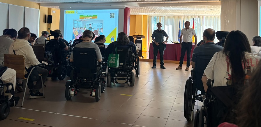 Personas en una salón escuchando la charla de un agente de la guardia civil.