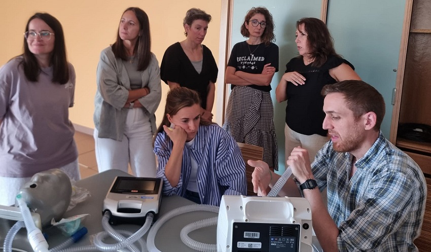 Personas participando en una explicación con aparatos para fisioterapia respiratoria